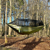DD Recycled Frontline Hammock set up in a forest with bug netting, showcasing its eco-friendly design made from recycled plastic.
